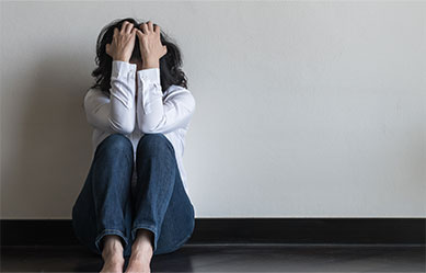 Woman sitting on the floor with head in hands, representing sex crimes