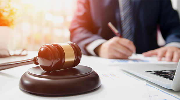 Judge's gavel on a desk with a lawyer writing in the background, representing legal services